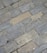 Gray and beige stone tiles laid out in a rectangular brick pattern. The surface appears weathered with some small cracks and variations in texture and color, giving it a rugged and natural appearance.