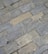 Gray and beige stone tiles laid out in a rectangular brick pattern. The surface appears weathered with some small cracks and variations in texture and color, giving it a rugged and natural appearance.