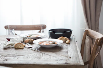 A cozy table setting with a plate of creamy risotto and a glass of red wine, bathed in natural light.