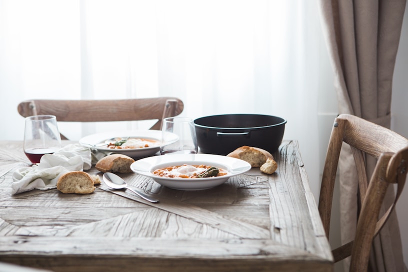 A warm, inviting shot of a rustic wooden table set with steaming bowls of homemade soup and fresh bread.
