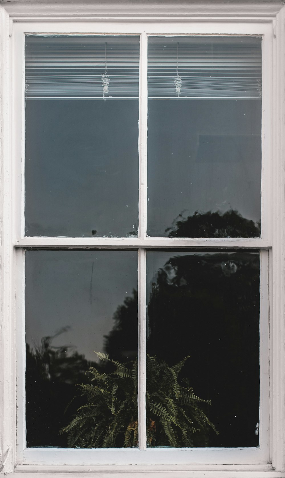 Fenêtre à panneau de verre à cadre en bois blanc avec stores blancs