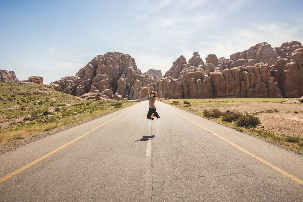 Mujer saltando en medio del camino