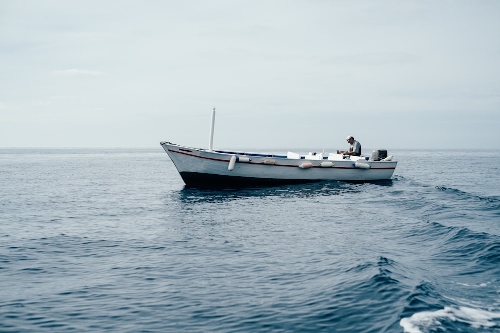 man sitting on boar in ocean