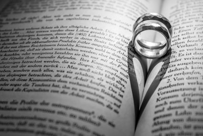 A close-up of intertwined wedding rings resting on a vintage book.