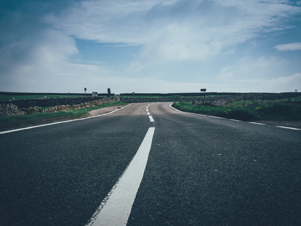 concrete road leading to green grass field