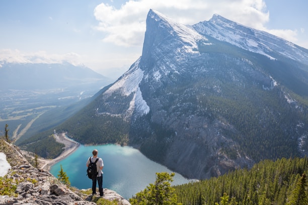 aerial photography of man standing on hill looking and a mountain trek and journey spirit