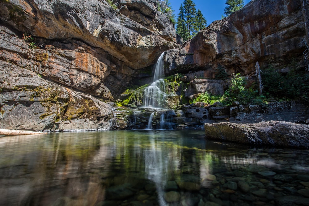 water falls in between brown rocks