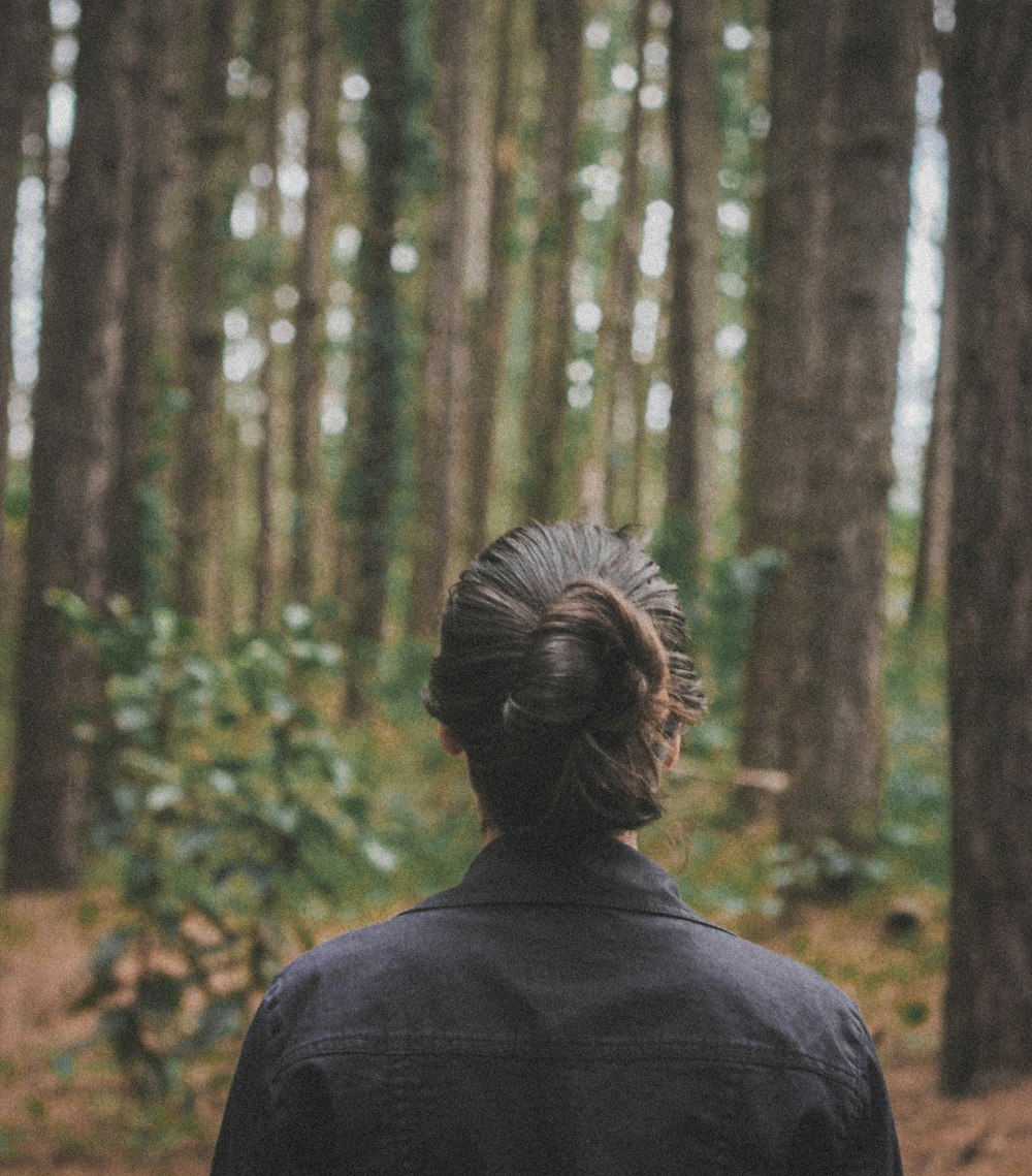 uma mulher em pé na floresta olhando para as árvores