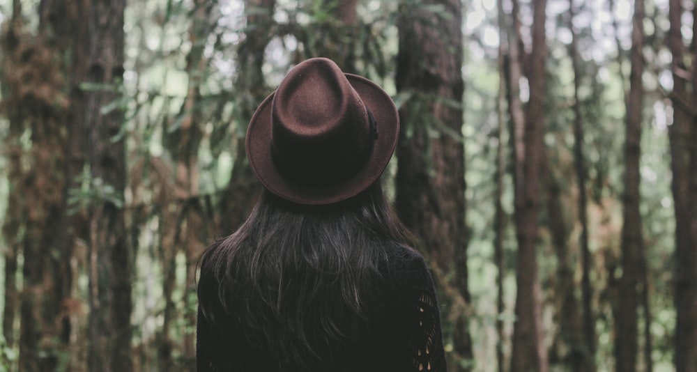 personne portant un chapeau face aux arbres