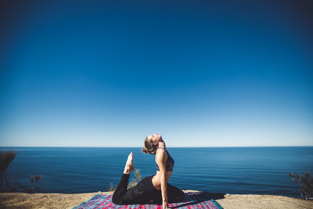 woman wearing black top and pants stretching body on mat