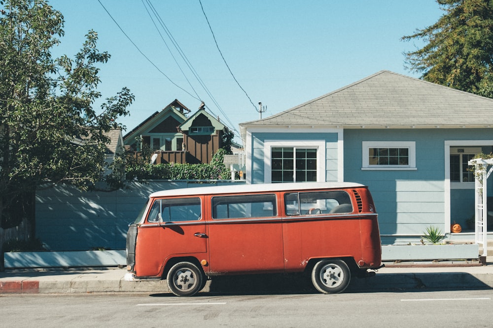 Volkswagen Samba rouge garée devant une maison turquoise