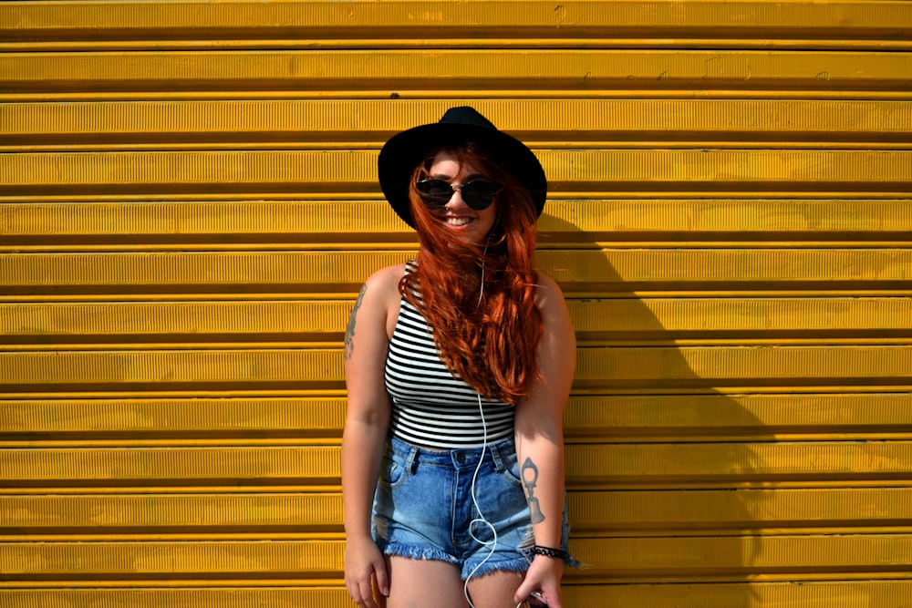 A redhead woman standing in front of a yellow wall.