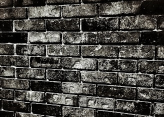 Rough-textured brick wall with dark mortar lines, showcasing an aged, worn appearance.