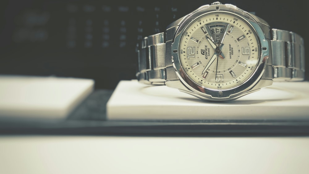 relógio analógico de moldura prateada redonda com pulseira de link no quadro branco