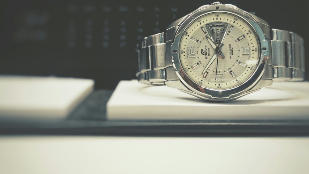 round silver-colored bezel analog watch with link bracelet on white board