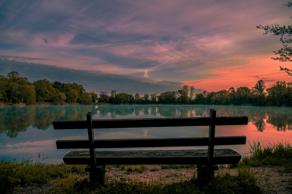 brown wooden bench near lake during daytime