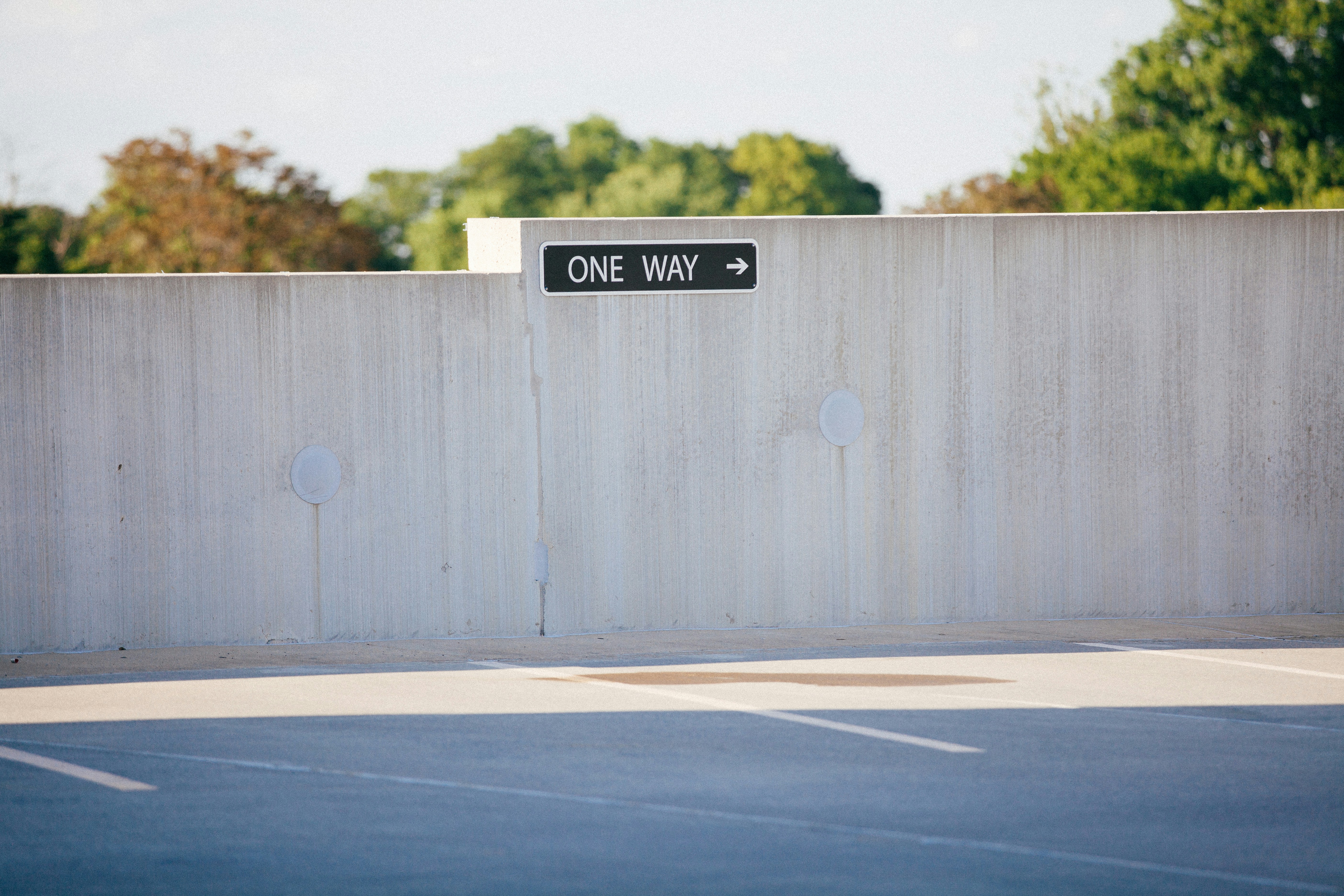 black and white one way signage on gray concrete wall, One way sign