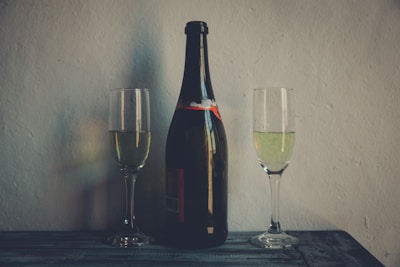 A close-up of a wine bottle and glasses set on a rustic wooden table.
