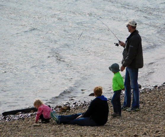 A happy family fishing together, with children safely using segurapez-covered hooks.