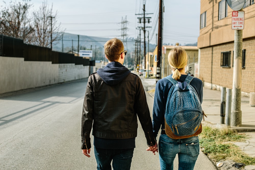 man holding hands of woman walks on concrete road