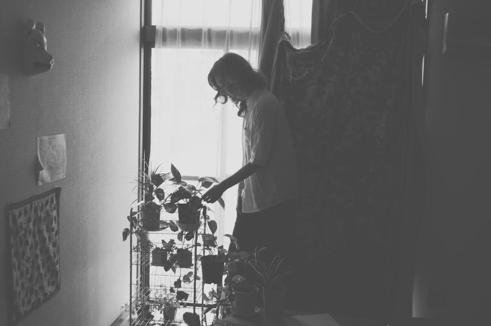 woman standing beside plant grayscale photography