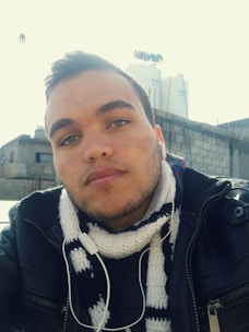 Person enjoying music outdoors wearing modern, stylish earbuds with a cityscape background.