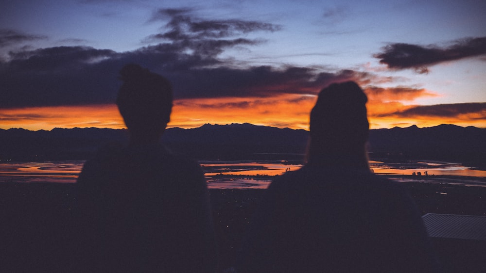 silhouette photo of two women starring at sunset