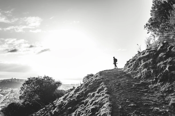A traveler consulting a map with a backpack and a bright sunrise in the background.