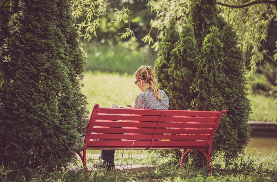 woman sitting on red wooden bench