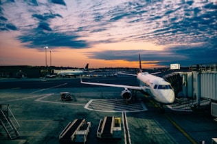 white airplane near trailers during sunset