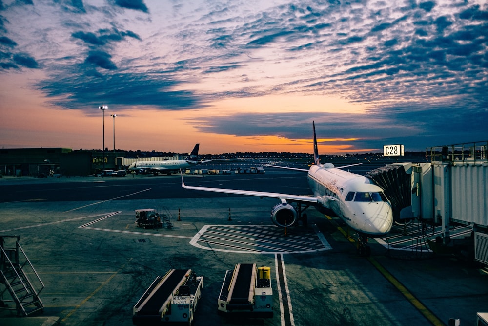 avion blanc près des remorques au coucher du soleil