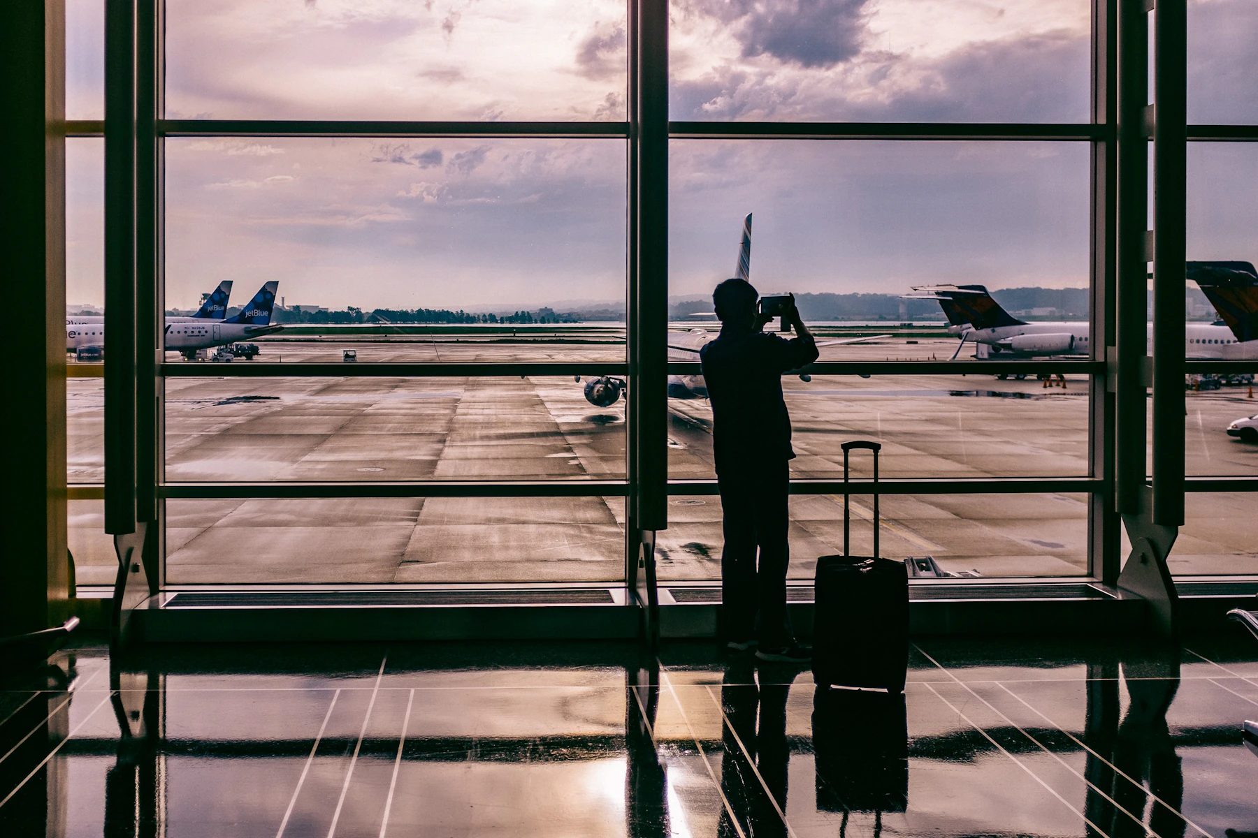 Traveller looking through an airport window toward aircraft on the runway