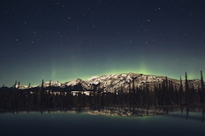 A serene lakeside view under the northern lights, evoking the spirit of old Finland.