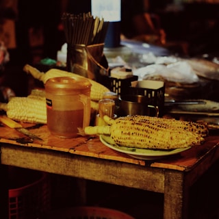 Rustic wooden table displaying freshly made pamonha wrapped in corn husks.