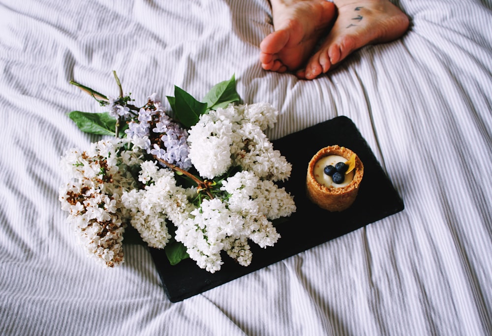 un plateau avec des fleurs et une bougie sur un lit