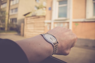 A person wearing a stylish wristwatch while checking the time against a blurred cityscape background.