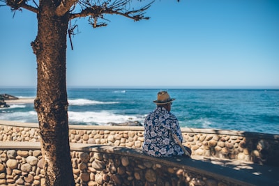 man sitting facing sea