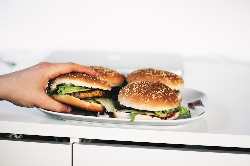 person holding hamburger on plate