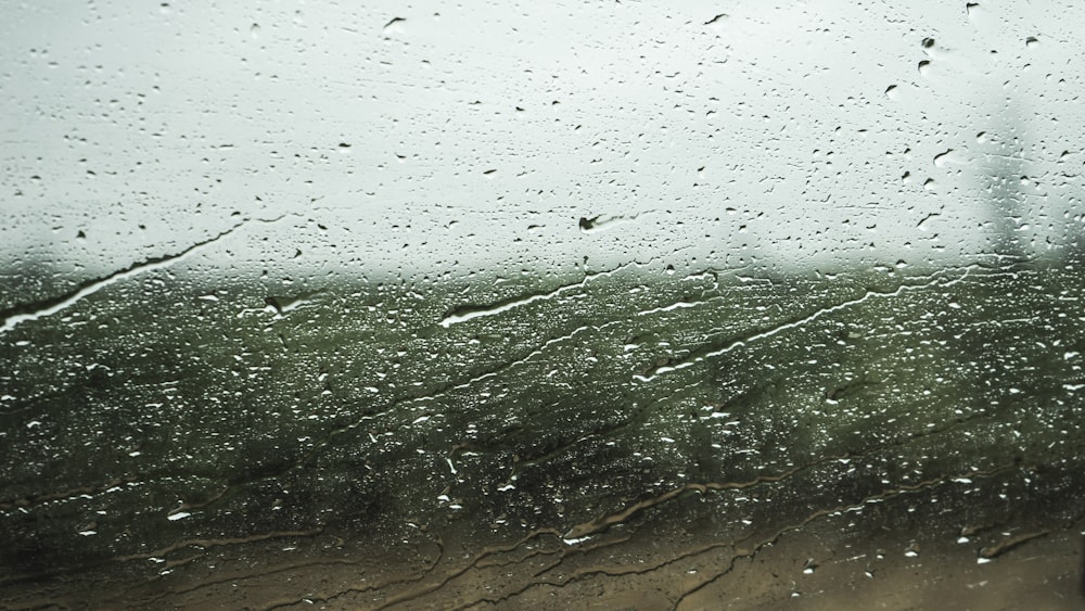a view of a field through a rain covered window