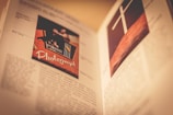 An open book with detailed images and text. The left page features a photo labeled 'Photograph' with a vintage camera and colorful elements. The right page displays an image of a cross on a wooden background.