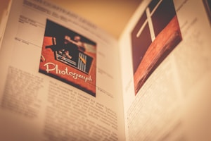 An open book with detailed images and text. The left page features a photo labeled 'Photograph' with a vintage camera and colorful elements. The right page displays an image of a cross on a wooden background.