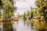 A serene scene of colorful boats floating along a river, surrounded by lush greenery. The boats have vibrant decorations and are reminiscent of traditional Mexican designs. There are people on the boats, enjoying a leisurely ride, and the water reflects the greenery and boat colors.
