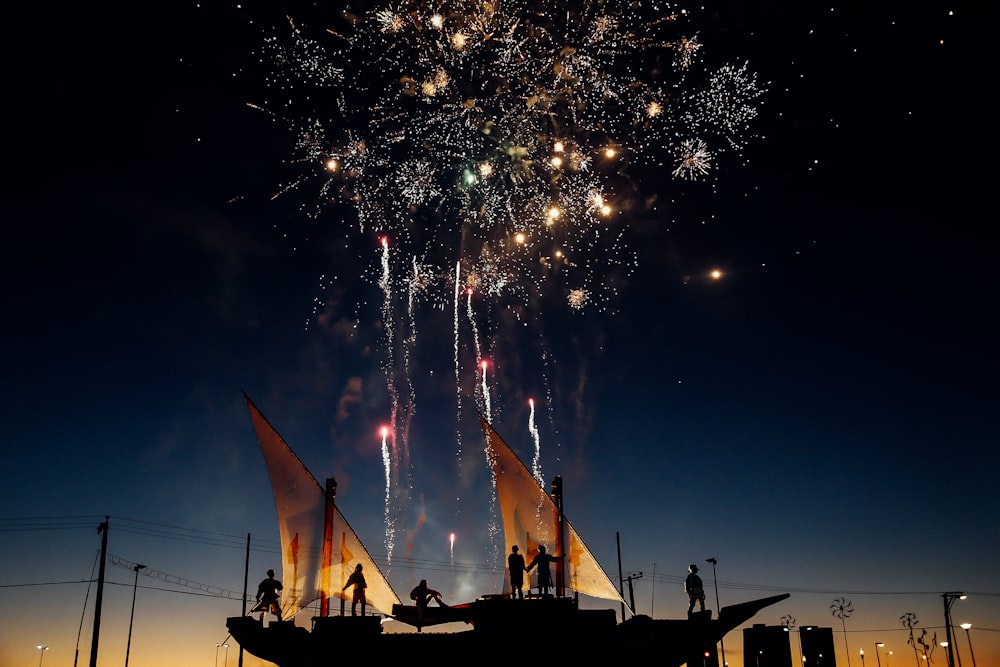空に浮かぶ花火を見ながら立っている人のシルエット写真