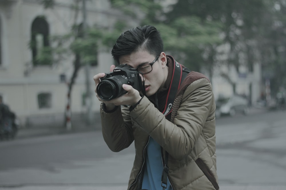 fotografía de enfoque superficial de hombre tomando fotografía sosteniendo su cámara