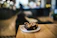 Close-up of a smiling woman enjoying a decadent chocolate brownie in a cozy, softly lit bakery setting.