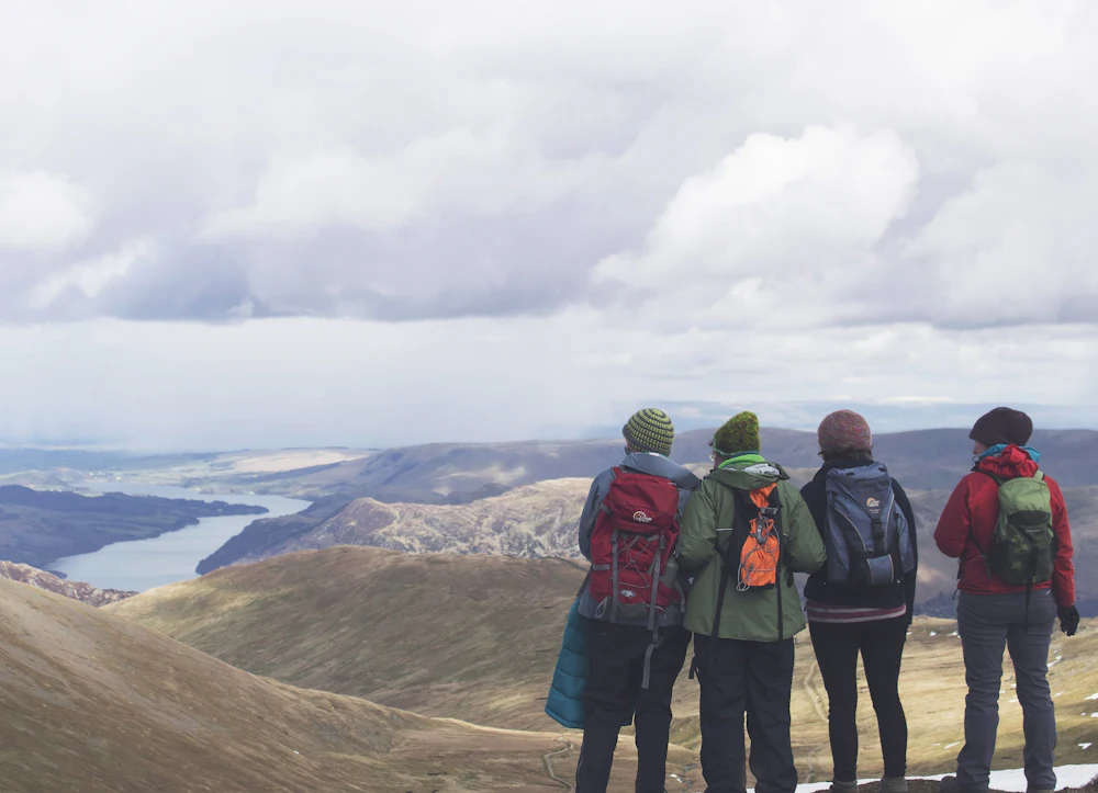 Four friends looking out over a lake and mountains