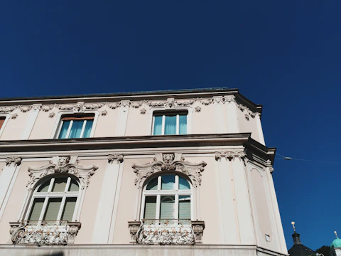 A bright, well-maintained building facade showing smooth plaster and fresh paint under a clear sky.