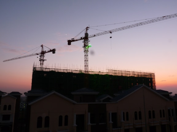 Construction site with cranes and emerging building structures at sunset