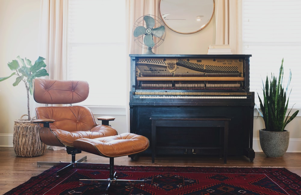 black upright piano near brown leather padded chair