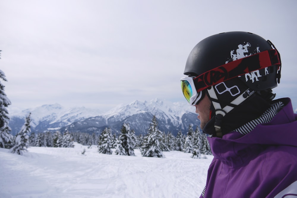 Mann mit schwarzem Helm und Schneebrille unter weißem Himmel